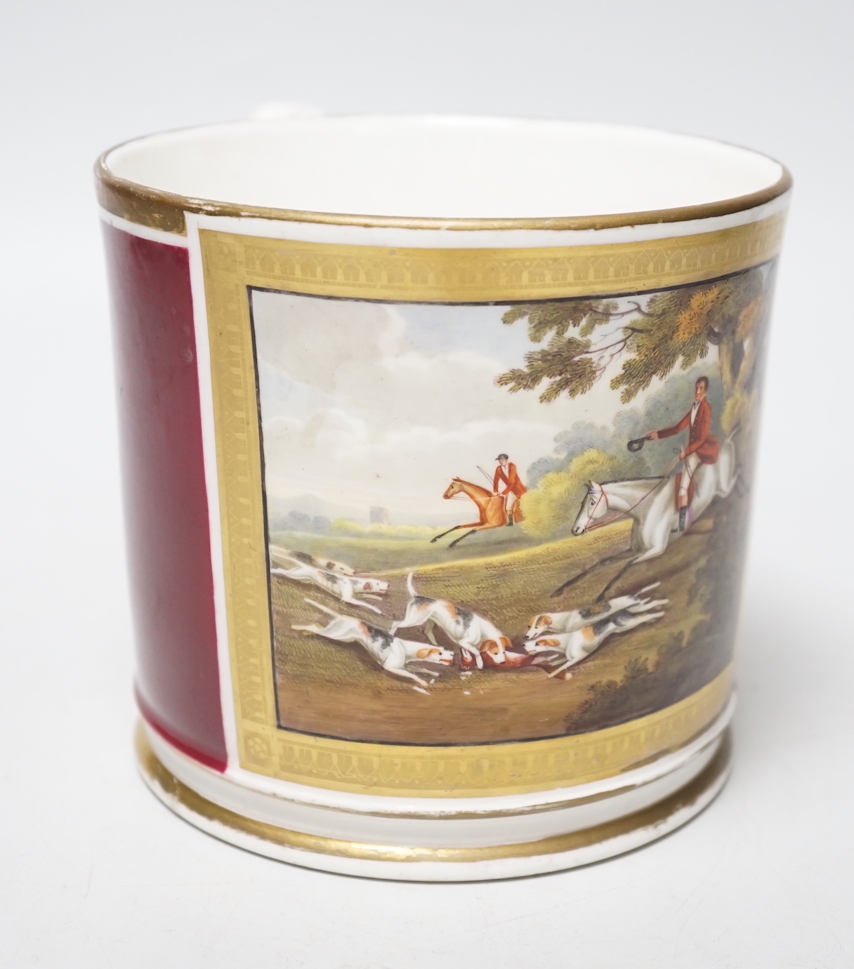 A 19th century English porcelain mug painted horses and riders with hunting dogs in a chase scene, the mug having a crimson ground, probably Chamberlains or Grainger’s Worcester, some old re-gilding